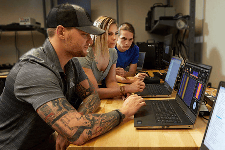 Three 3dB Labs engineers at a lab bench watching a spectrum waterfall display on a laptop